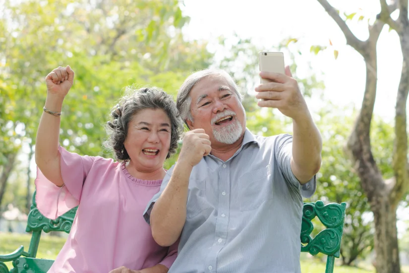 elderly people lifestyles and communication technology. Happy grandparent using tablet video call and talking with family in the park.