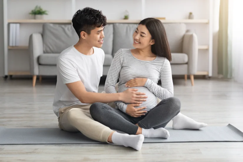 Happy asian man touching his pregnant wife big belly